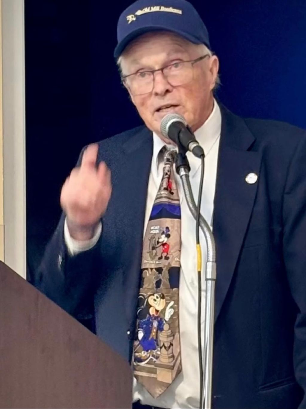 Gordon Clay, wearing an Old Mill Boathouse cap, speaking at a community event